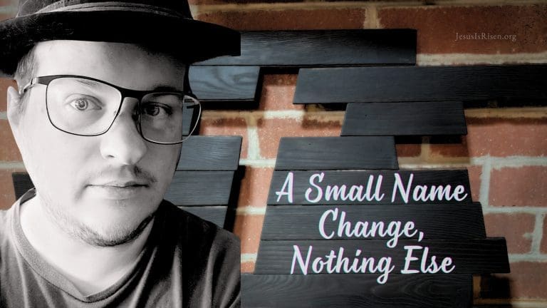 Black-and-white portrait of a man wearing glasses and a hat, standing beside a handmade wooden cross mounted on a brick wall, with the words “A Small Name Change, Nothing Else” overlaid on dark wooden boards.