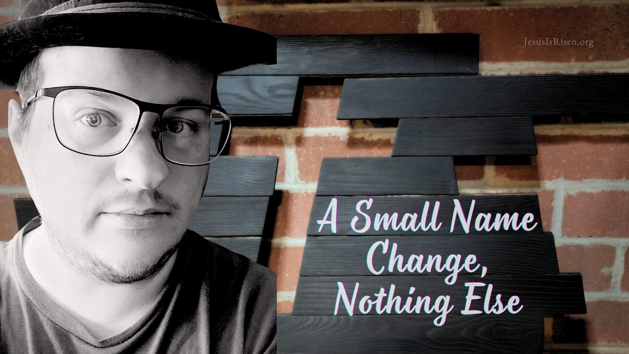 Black-and-white portrait of a man wearing glasses and a hat, standing beside a handmade wooden cross mounted on a brick wall, with the words “A Small Name Change, Nothing Else” overlaid on dark wooden boards.